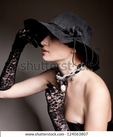 mysterious woman dressed in a black hat and lace gloves