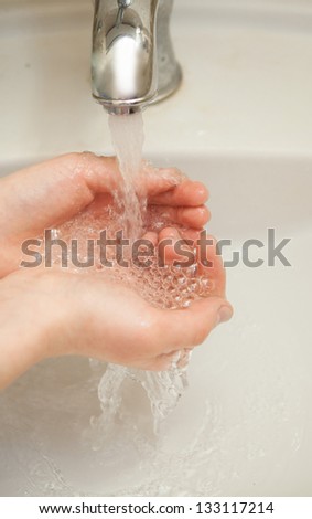 man washing his hands under a stream of water from the tap in the bathroom