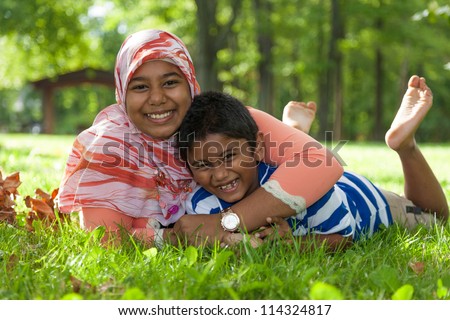 Outdoor portrait of indian brother and sister playing