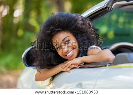 Young black teenage driver seated in her new convertible car - African people