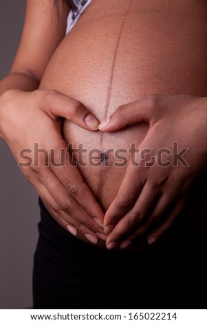 Young pregnant african american woman belly, over dark background  - Black people