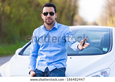 Young latin american driver holding car keys driving his new car