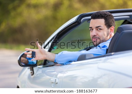 Young black latin american driver holding car keys driving his new car