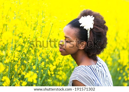 Outdoor portrait of a young beautiful african american woman in a rape colza field - Black people