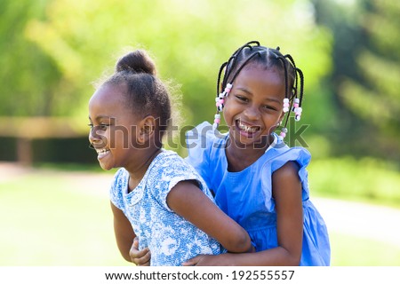 Outdoor portrait of a cute young black sisters laughing - African people