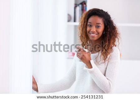 African American woman in her living room drinking holding a coffee tea mug - Black people