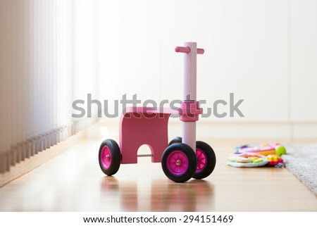 Pink wood bike toy in the middle of the living room