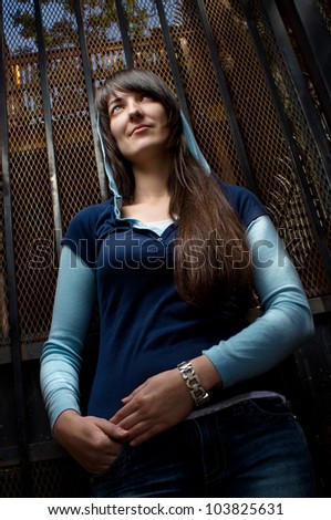 young girl i? blue clothes  stands at metal gate
