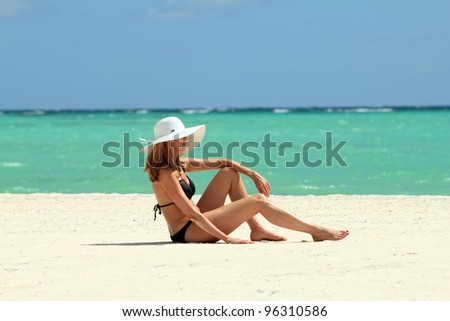 Bikini woman with white hat on a tropical beach