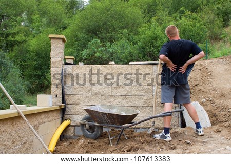 back pain, bricklayer builds a wall