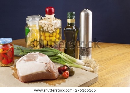 Fresh raw pork on a cutting board with vegetables and spices, preparation of meat for grilling