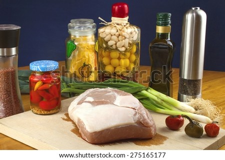 Fresh raw pork on a cutting board with vegetables and spices, preparation of meat for grilling