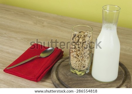 oatmeal flakes in a glassful next to the milk carafe. Healthy breakfast with fiber. Fresh milk in the glass and muesli breakfast