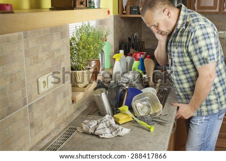 Man washing dirty dishes in the kitchen sink. Domestic cleaning up after the party.
