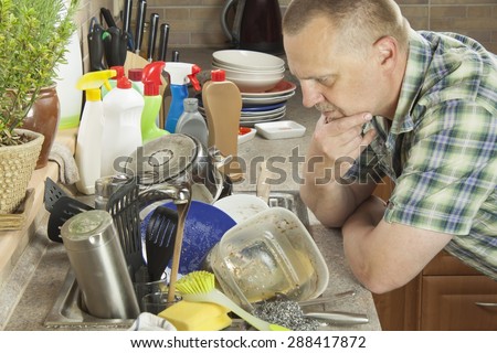 Man washing dirty dishes in the kitchen sink. Domestic cleaning up after the party.