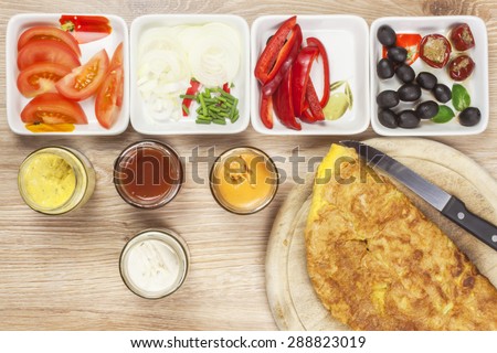 Scrambled egg omelet with vegetables on a wooden table. Preparation of fast food home.