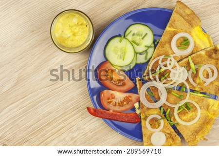 Preparing a delicious dinner. Scrambled egg omelet with vegetables on a wooden table. Preparation of fast food home.