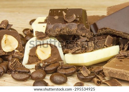 Pieces of chocolate on a wooden board. Sweet chocolate pleasure on the table.