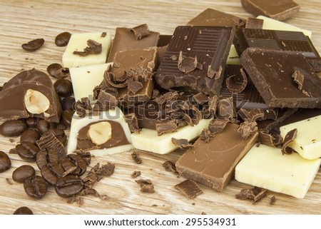 Pieces of chocolate on a wooden board. Sweet chocolate pleasure on the table.