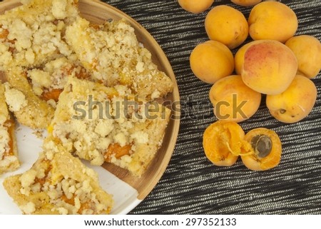 Homemade apricot cake on a plate. Freshly picked apricots on a wooden table. Homemade dessert of summer fruits.