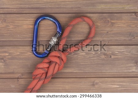 Figure eight knot with climbing carabiner on wooden background. The concept of selling advertising space for climbing equipment.