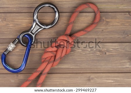 Figure eight knot with climbing carabiner and rappel eight on wooden background. The concept of selling advertising space for climbing equipment.