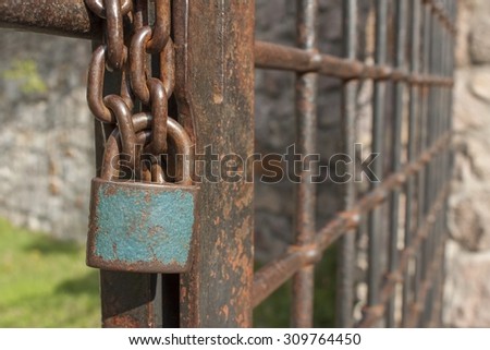The lock on the chain. Old rusty chain with a lock on the iron gate. Symbol imprisonment and slavery. Property security chain. Closed iron gate with a lock.