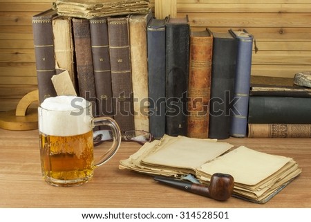 Cool glass of beer on the table. Relax with a good book with a glass of cold beer. The concept relax with a good beer. Pouring a glass of beer for readers of the book. Alcohol and study.