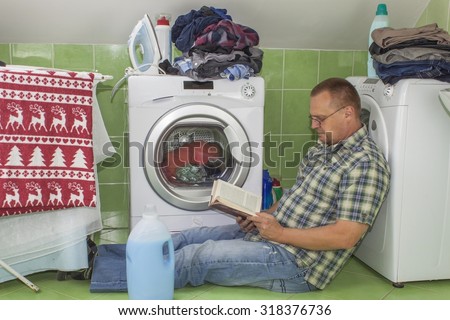 A man washes clothes in the washing machine. Housework men. Man helping his wife when washing clothes. The division of housework. Man Near The Washing Machine.