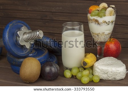 Diet for athletes build muscle mass. Protein snack. Dairy products and dumbbells. fresh milk in the glass and muesli breakfast on a wooden table. Oatmeal with milk and curd, meals for athletes