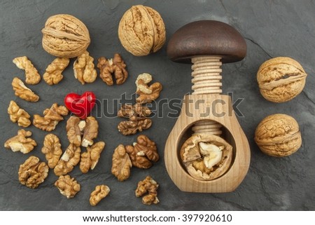 Walnut kernels and whole walnuts on slate.  Walnuts and wooden nutcracker. We like walnuts. Advertising on walnuts.