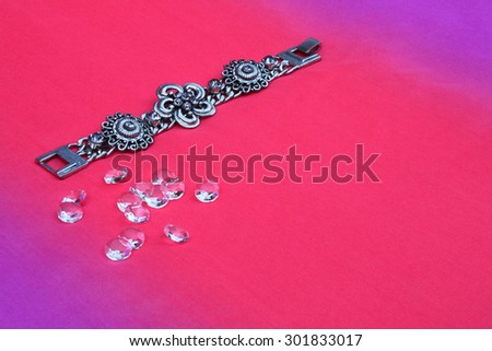 Silver bracelet with purple gems on pink background