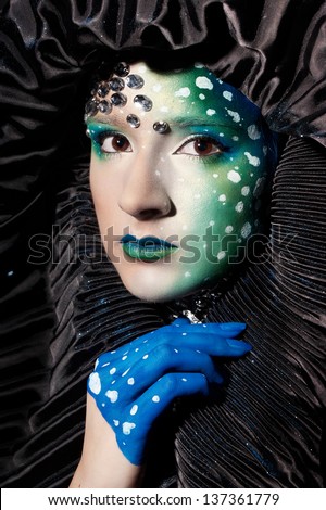 Woman with futuristic makeup and wearing a black hat
