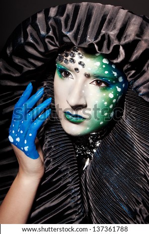 Woman with futuristic makeup and wearing a black hat