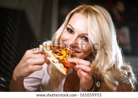 Young woman in a white shirt eats pizza