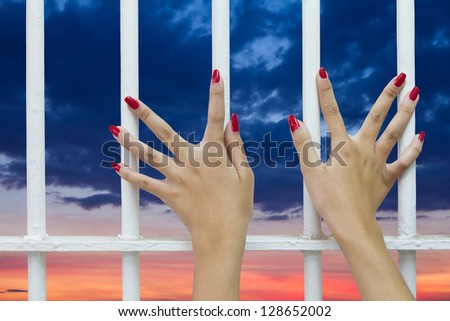 Red finger nails of women who were imprisoned in a cage.