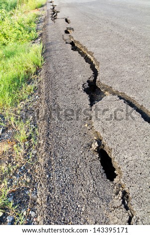 Side view asphalt road broken due to collapsing ground until the grass grows.