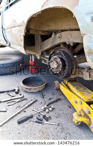 Old cars are visible hub, which has been damaged and need to wait for the spare tire to be changed.