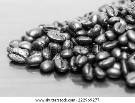 Black and white close-up images of coffee resting on a mirror reflects light.