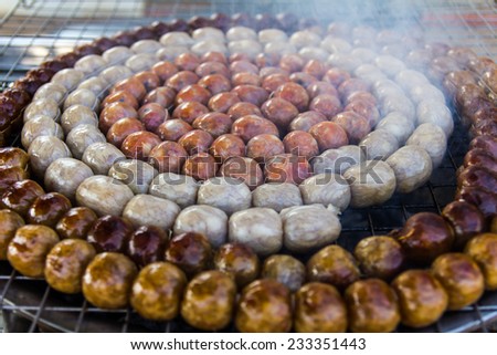 Sausage small circles on the grid-iron grill with smoke over charcoal.