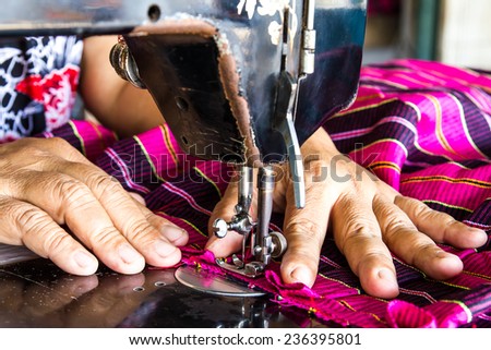 Woman hand sewn fabric pink repairs on old sewing machine.