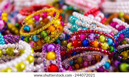 Background of colorful bead bracelets piled together so many different retailers.