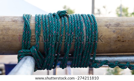 Close up of green nylon rope tied to a bundle of bamboo to steel spiral together.