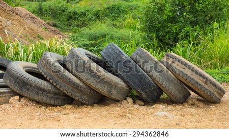 Many old tires stacked pile on the ground close to the grass to wait for Recycling.
