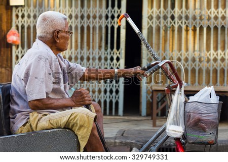 PHICHIT THAILAND-JUNE 19:\
Thailand elderly man whose wheelchair adapted bike lever handle and a steel door into the house..On June 19, 2015 in \
Phichit, Thailand.
