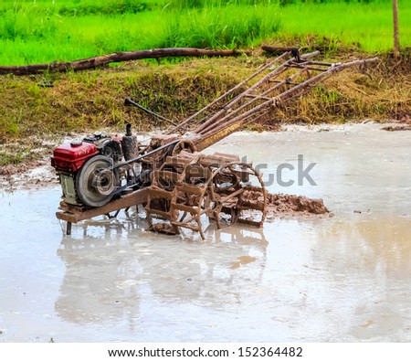 Thai farmer using walking tractors for cultivated soil for rice plantation at Thailand.