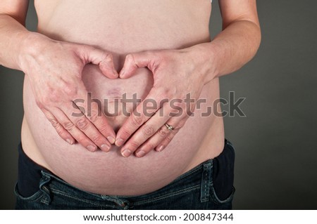 Heart shaped hands on pregnancy bump