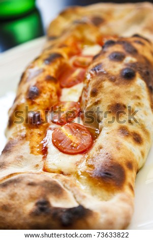 Gourmet rolled pizza, with mozzarella cheese and cherry tomatoes.