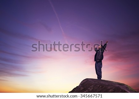 man with hands raised in the sunset concept for religion, worship, prayer and praise