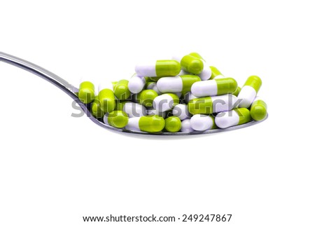 Spoon with capsules Greens on a white background